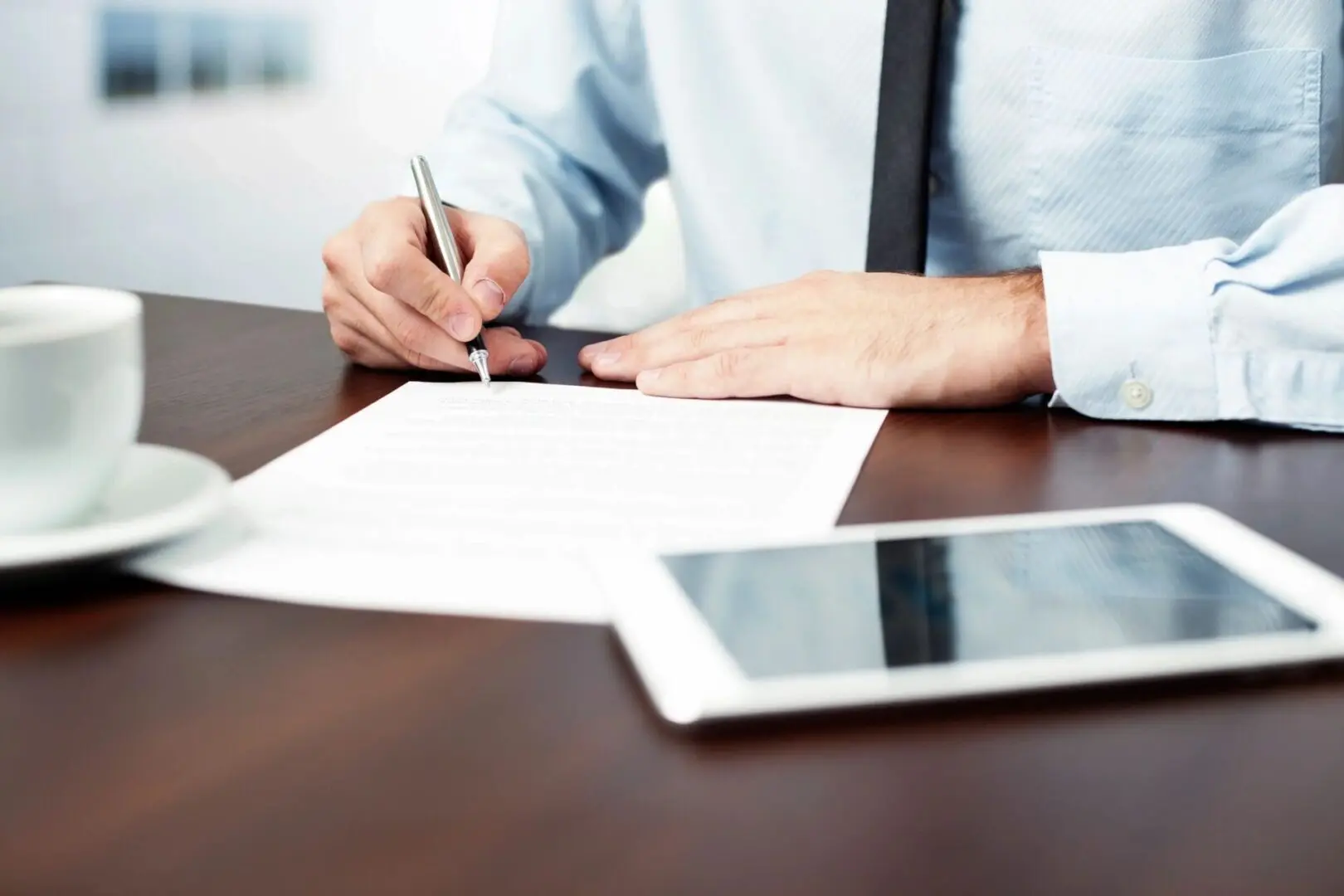 A person is writing on paper with a tablet.