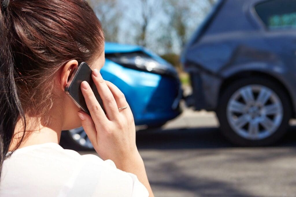 A woman on her cell phone near an accident.